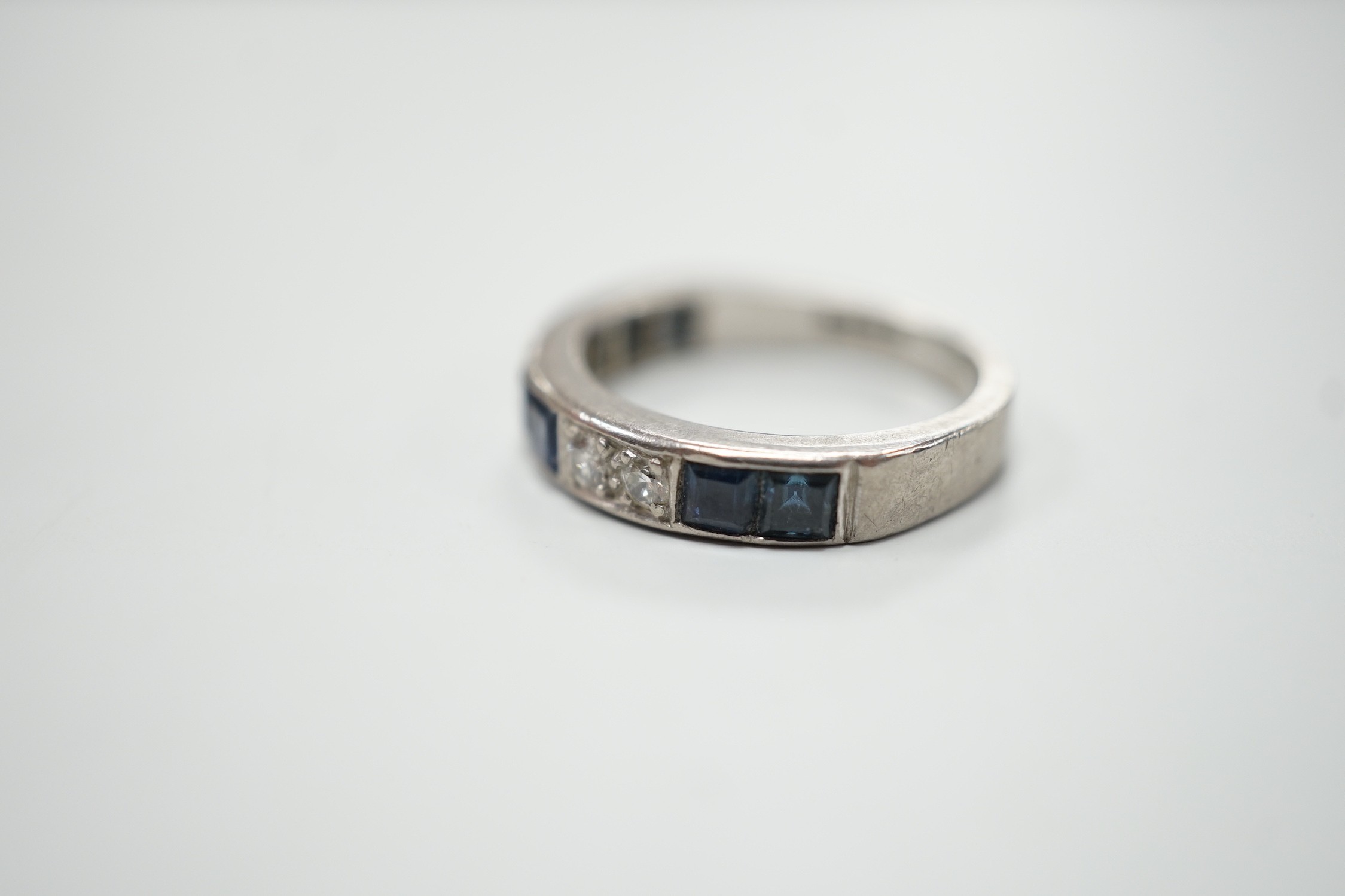 A modern 18ct white gold, six stone sapphire and four stone diamond set half eternity ring, size M, gross weight 5.2 grams.